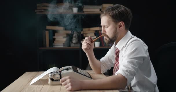 Бородатый писатель курит на машинке — стоковое видео
