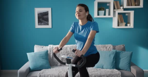 Aktywna dziewczyna w odzieży sportowej ćwiczy na rowerze treningowym — Wideo stockowe