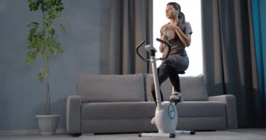 Young girl working out at home on exercise bike