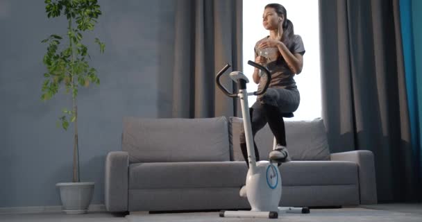 Young girl working out at home on exercise bike — 비디오