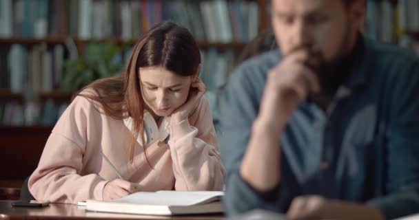 Mujer joven estudiando en la biblioteca — Vídeos de Stock