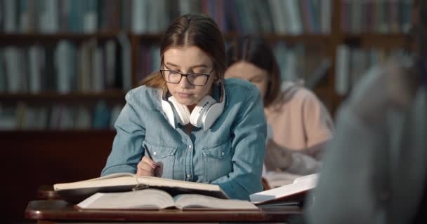 Estudante do sexo feminino leitura na biblioteca — Vídeo de Stock