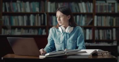 Female Student with Laptop Reading in Library