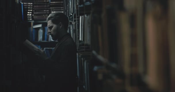 Man Choosing Book in Dark Library — Stockvideo