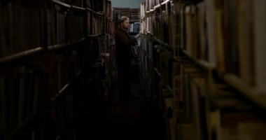 Man Choosing Book in Dark Library