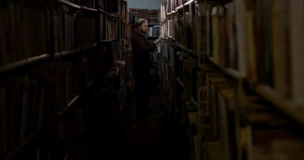 Man Choosing Book in Dark Library — Stock videók