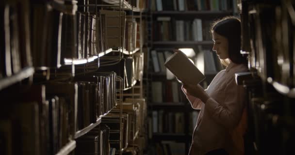 Femme avec livre dans la bibliothèque sombre — Video