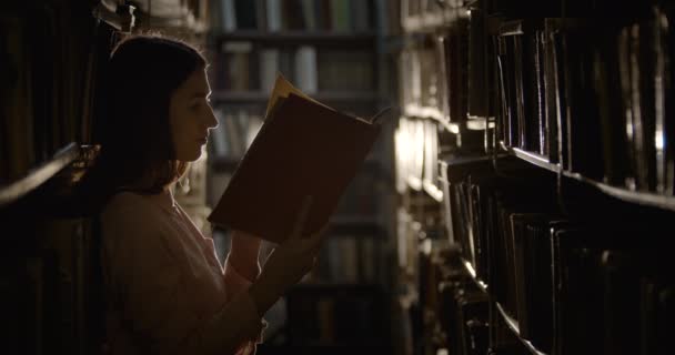 Libro de lectura de mujer en la biblioteca oscura — Vídeos de Stock