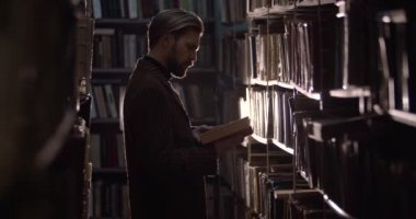 Bearded Man Reading Dusty Book in Library