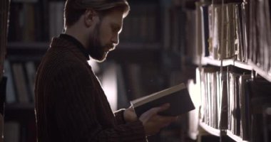 Bearded Man Reading Dusty Book in Library