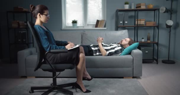 Hombre deprimido acostado en el sofá en la oficina de psicólogos — Vídeos de Stock