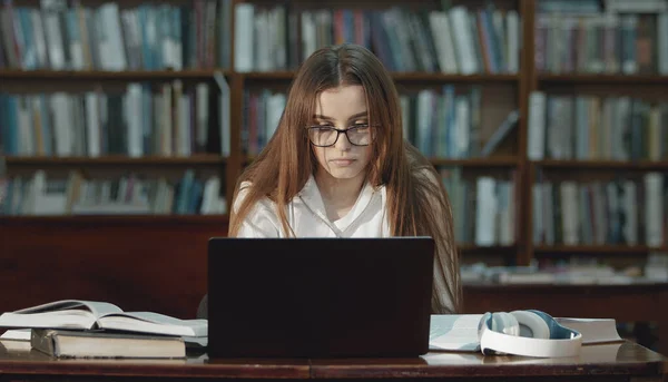 Teenager working laptop in library — 스톡 사진