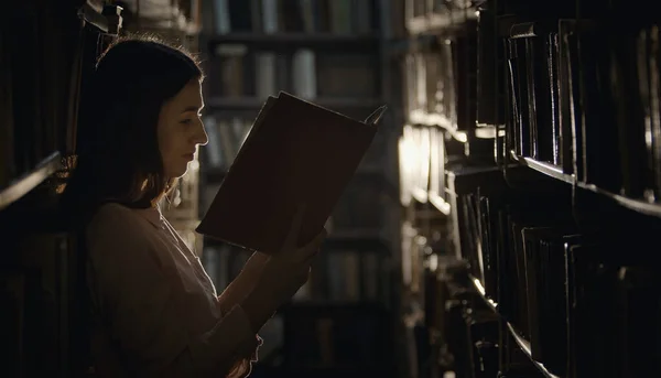 Woman reading book, dark library — Zdjęcie stockowe