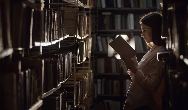 Lady reading book, dark library — Stock Fotó