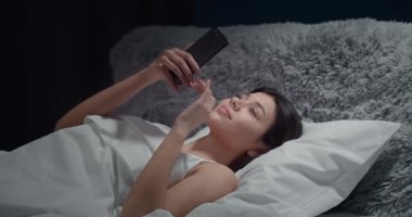 Yatak odasında Smartphone Kaydıran Kadın