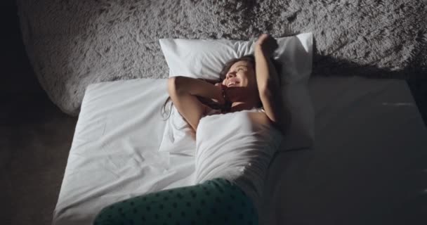 Femme heureuse dans les écouteurs au lit — Video