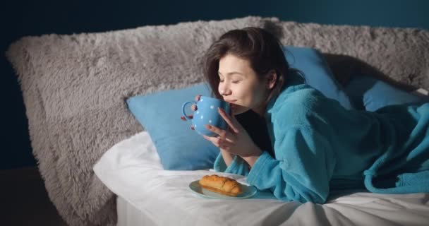 Счастливая женщина пьет утренний кофе в постели — стоковое видео
