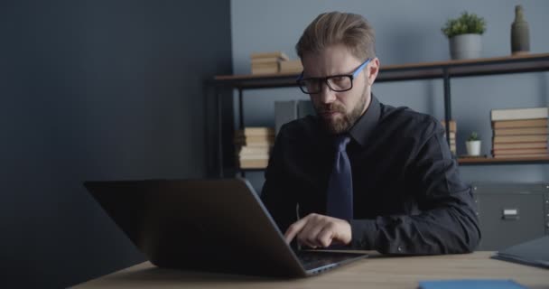 Hombre con gafas de vista Trabajando en el ordenador portátil en la oficina — Vídeo de stock