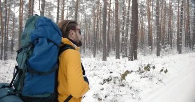 Sırt çantalı neşeli yürüyüşçü karlı ormanda yürüyor