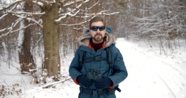 Karlı ormanda yürüyen ve dürbün kullanan olgun bir adam.