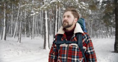 Sakallı yürüyüşçü, buz gibi ormanda büyük bir sırt çantası taşıyor.