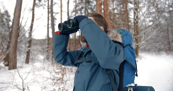 Baard man met een verrekijker in besneeuwd bos — Stockvideo