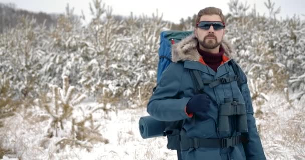 Hombre barbudo parado entre pinos cubiertos de nieve — Vídeo de stock