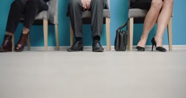 Group of three people sitting on chairs in queue line