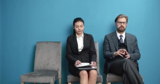 Нервовий чоловік і жінка чекають у синьому залі для зустрічі — стокове відео