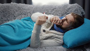 Sick couching man looking termometer