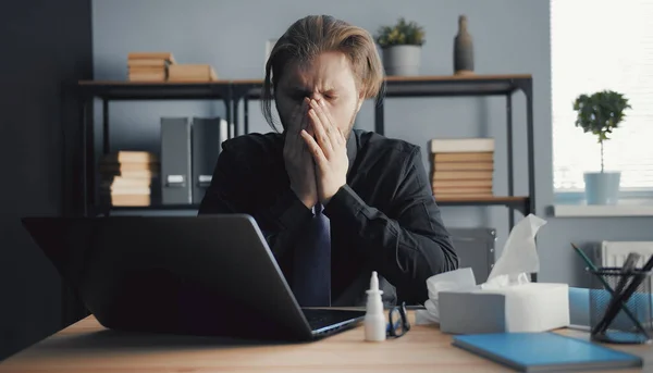 Sick man sneezing while working — Stock Fotó