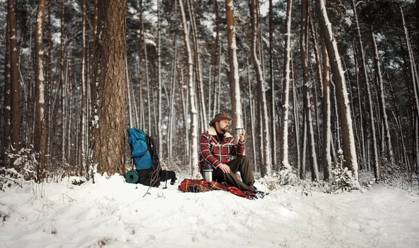 Outdoorsman drinking tea, winter forest — Zdjęcie stockowe