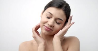 Koyu saçlı hassas bir bayan sağlıklı ve taze bir ten gösteriyor.