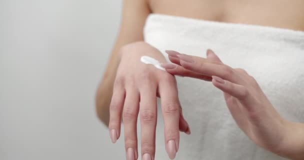 Primer plano de la mujer joven aplicando crema hidratante en las manos — Vídeo de stock