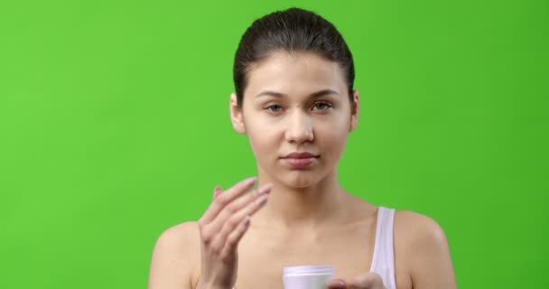 Gadis yang mempesona menggunakan krim kosmetik untuk melembabkan wajah — Stok Video