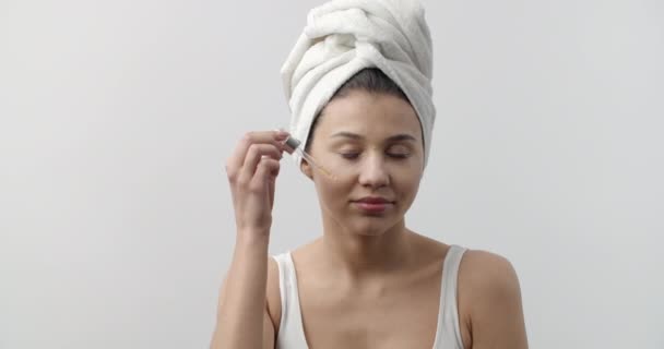 Portrait of pretty young woman applying serum on face — Stock Video