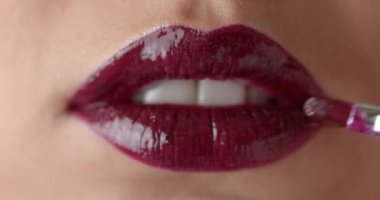 Extreme close up of female model applying marsala lipstick