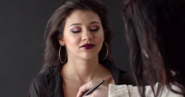 Female beautician doing body makeup with powder brush