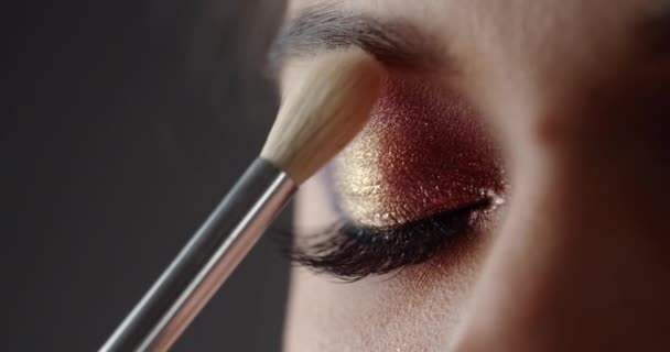 Makeup artist applying colorful eyeshadow on models eye — Wideo stockowe