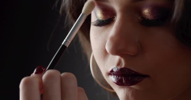 Очаровательная женщина с темными вьющимися волосами во время процесса макияжа — стоковое видео