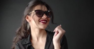 Pretty girl in sunglasses and black blouse dancing in studio