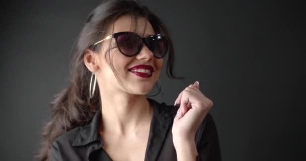 Красивая девушка в солнечных очках и черная блузка танцует в студии — стоковое видео