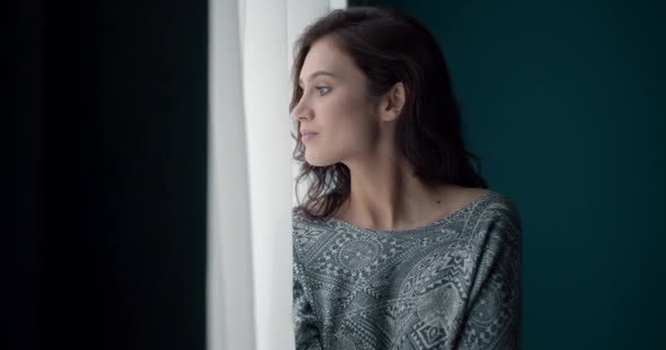 Mooi duur meisje staan in de buurt van raam thuis — Stockvideo