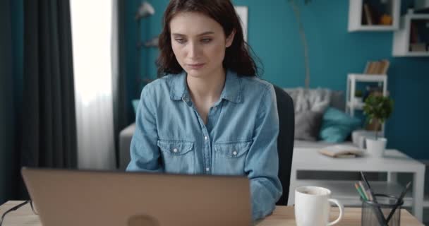 Bella ragazza seduta alla scrivania e digitando sul computer portatile — Video Stock