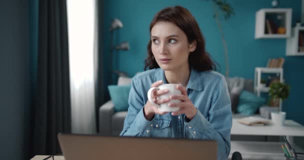 Уверенная женщина делает перерыв на кофе во время работы над ноутбуком — стоковое видео