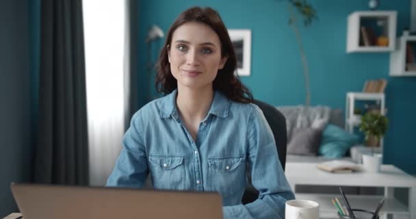 Retrato de niña sonriente sentada en la mesa con el ordenador portátil — Vídeos de Stock