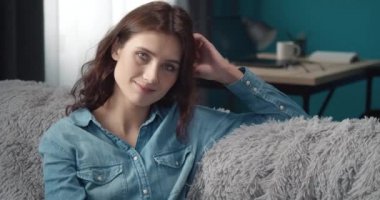 Kanepede oturan kot gömlekli çekici kadının portresi.