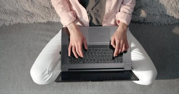 Vista superior da jovem sentada no sofá e digitando no laptop — Vídeo de Stock