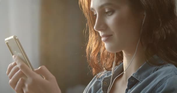 漂亮的女人带着智能手机待在家里 — 图库视频影像
