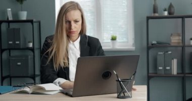 Ofiste laptopta çalışan kendinden emin olgun bir bayan.